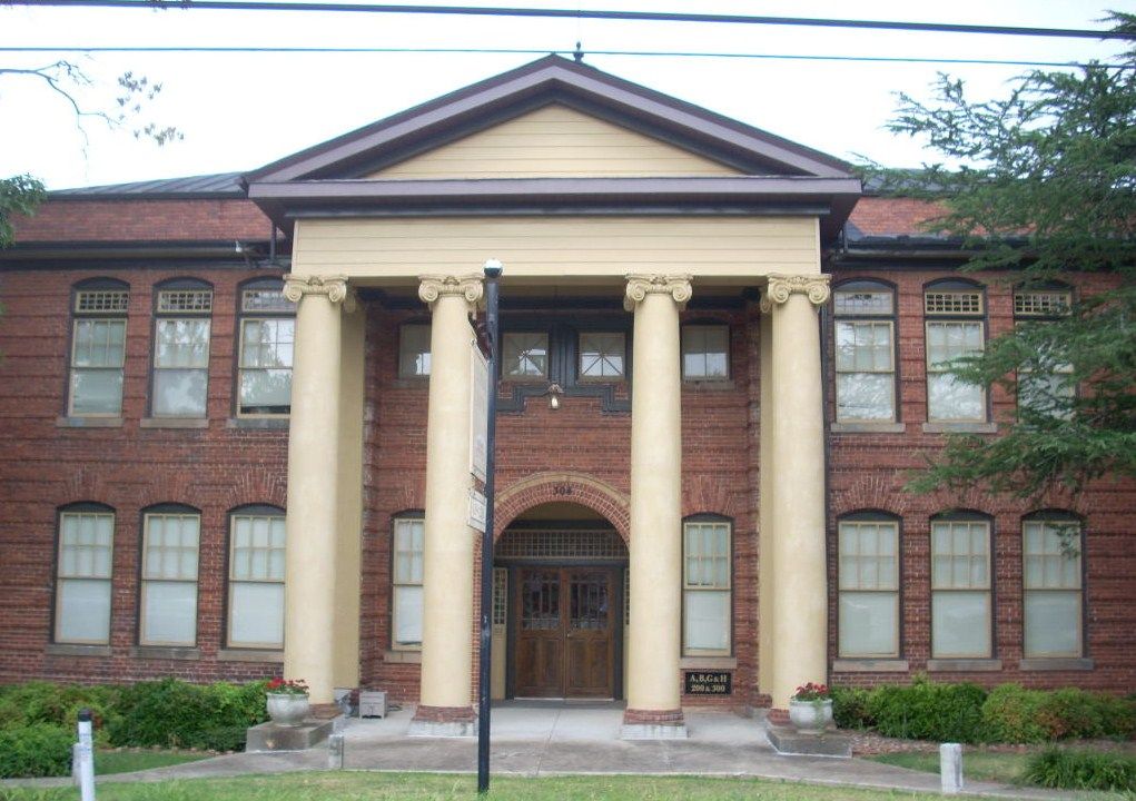 The old Central High School, a two-story red brick building with four tall cream columns at its entrance.