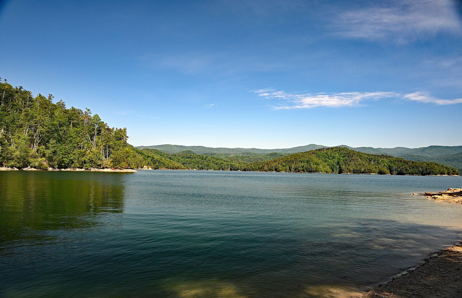 The wooded shore of Lake Jocassee with mountains behind
