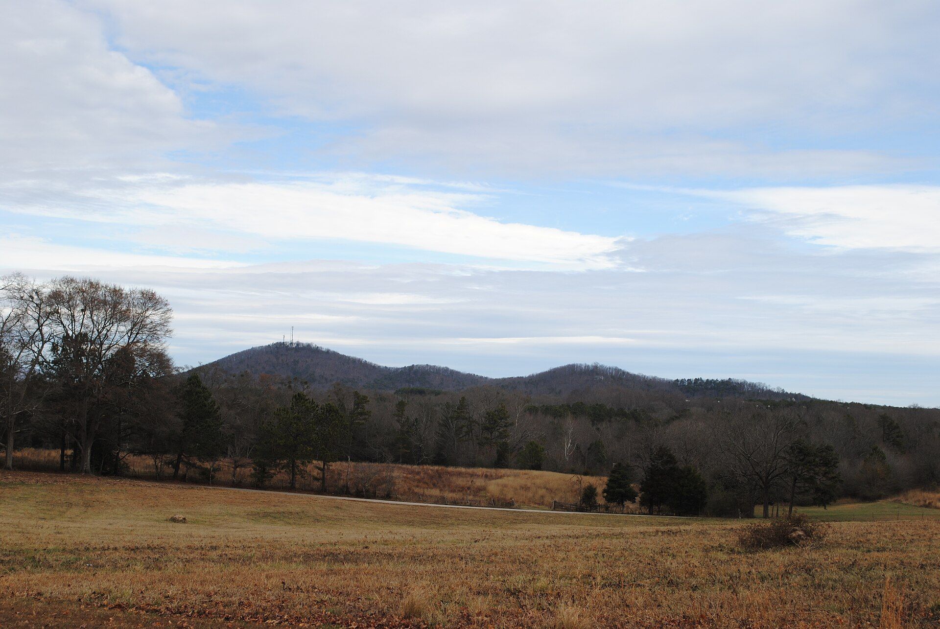 Open fields and wooded hills seen from Six Mile, with mountains beyond